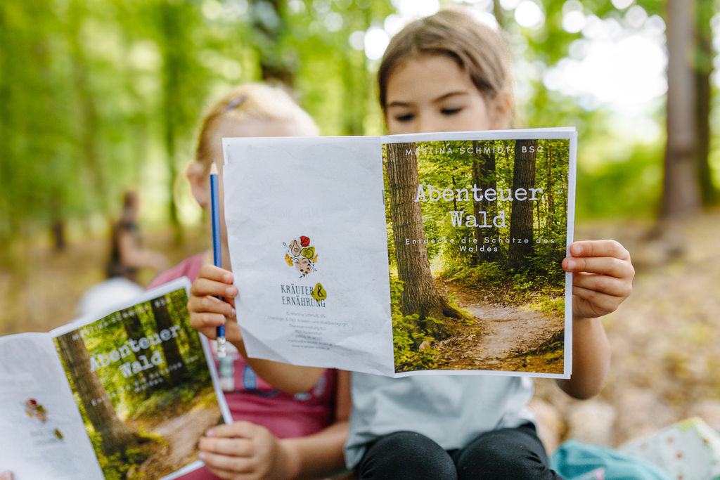 Waldwissen - Im Bild lesende Kinder im Wald